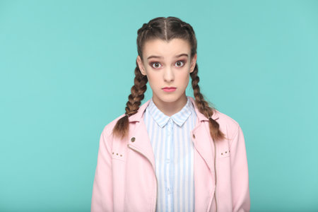 Portrait of shocked surprised teenager girl with braids wearing pink jacket looking at camera with...