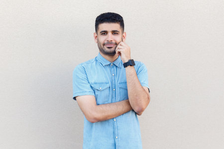 Portrait of handsome smiling calm man wearing denim shirt standing looking at camera with positive...