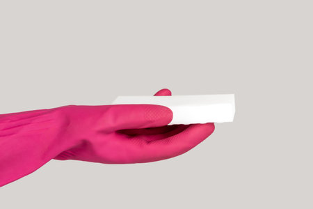 Closeup of woman hand in pink rubber glove holding dish washing white sponge cleaning service....