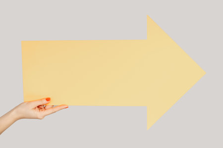Closeup of woman hand showing carton card yellow arrow indication aside, empty space for you...
