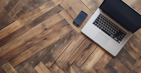 A laptop and mobile phone sitting on a wooden floor. Top view above the phone computer notebookの素材