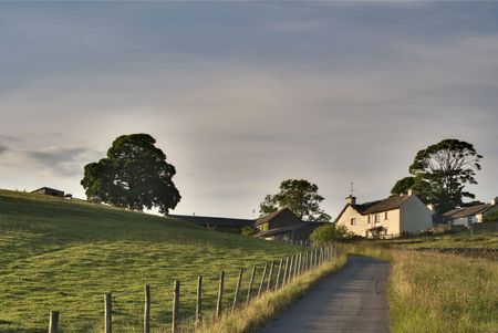 Rural road leading to a white farmhouse in the English Lake District