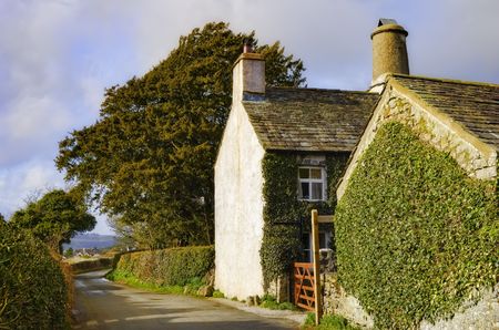 A view of the side of a quaint English cottage along the side of a narrow country roadの写真素材