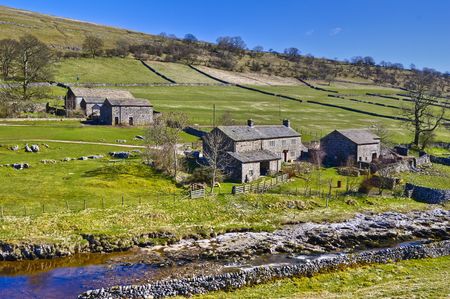 Scenic view of stone farm buildings in countryside with stream in foreground, Yockenthwaite, Wharfdale Valley, Yorkshire, England.の写真素材