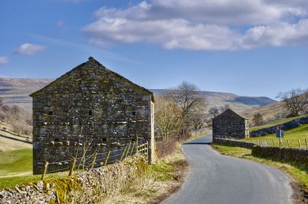 Exterior of two stone barns by countryside road, Wharfedale, Yorkshire Dales National Park, England.の写真素材