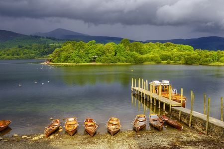 Scenic view of boats moored by wooden pier on Derwent Water, Lake District National Park, Cumbria, England.の写真素材