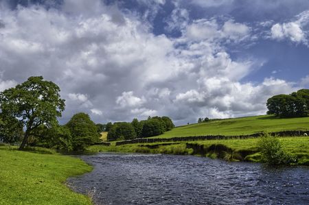 Scenic view of Hodder river in countryside under cloudscape, Forest of Bowland, Lancashire, England.の写真素材
