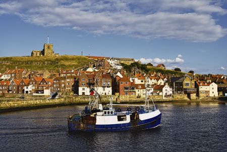 Fishing boat entering Whitby town harbor, North Yorkshire, Englandの写真素材