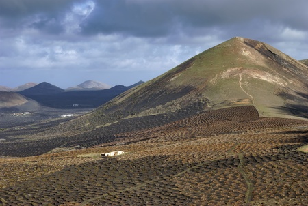 Scenic landscape of La Geria region with mountains and cloudscape in background, Lanzarote, Canary Islands, Spain.の写真素材