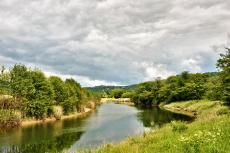 Calm waters of the River Leven flowing through lush countryside under a cloudy sky, Haverthwaite, Cumbria , Englandの写真素材
