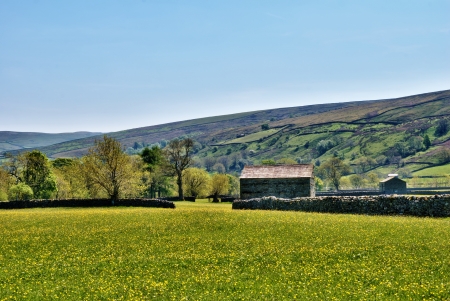 Old stone barn on a grassy meadow at the foor of a hill in the English countryside iin the Yorkshire Dales National Parkの写真素材