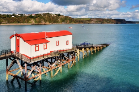 Beautiful view of a brightly painted,converted Lifeboat Station, with slipway stretching away into an undulant sea,at Tenby, Wales の写真素材