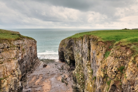 A view of Raming Hole, a coastal cleft formed from a weakness in the carboniferous limestone cliffs, at Stackpole, Pembrokeshire の写真素材