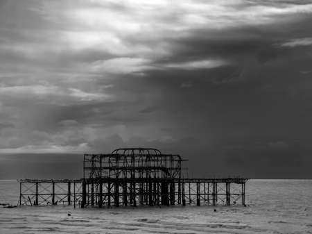 a silhouette of the West Pier, Brighton, under a dark, gloomy skyの写真素材