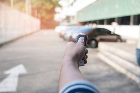 Hand holding remote key at car park background.の写真素材