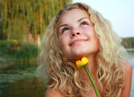 Portrait of the beautiful young girl of the blonde and curly hair against trees andの写真素材