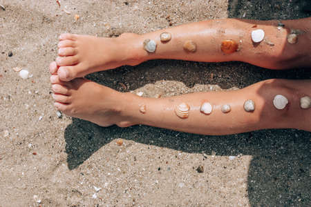 Little girl's feet are decorated with seashellsの写真素材