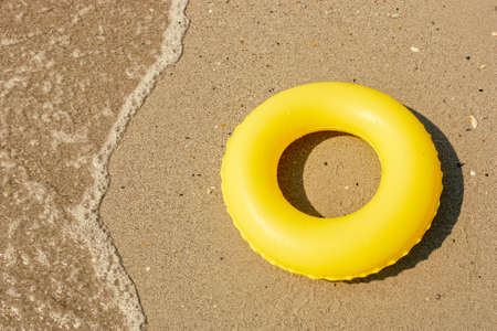Yellow color swim ring near sea on sunny dayの写真素材
