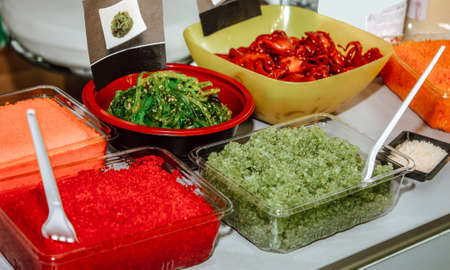 Flying fish roe, capelin roe, seaweed salad and baby octopus salad in a disposable dish