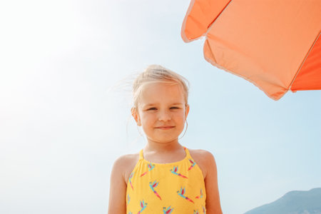 Little girl in a bathing suit near the umbrellaの写真素材