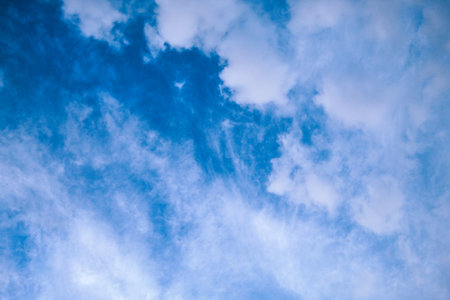 Blue sky with soft fluffy white clouds floating across it