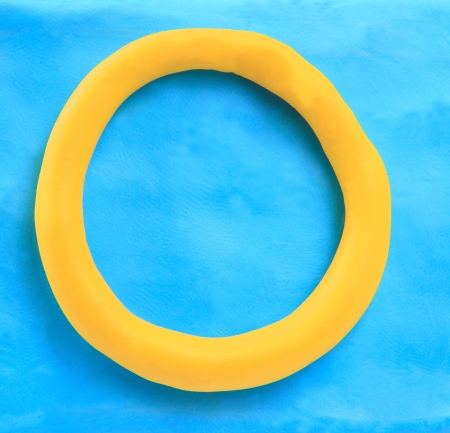 yellow clay alphabet letter with drop shadow on blue clay
