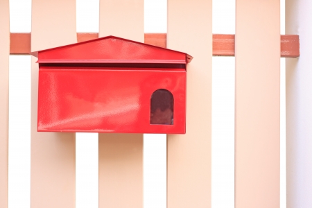 red mail box hanging on fenceの写真素材