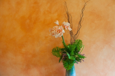 decorated flowers in jug in front of yellow wallの写真素材
