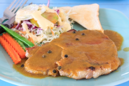 pork steak ready for eat in dish  with blue backgroundの写真素材