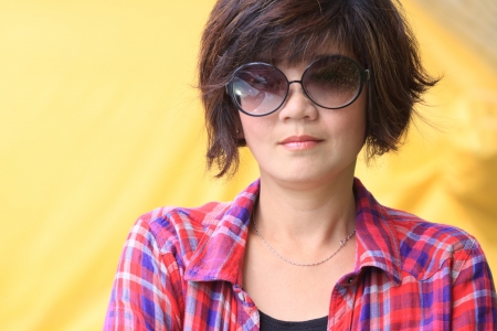 asian woman with eyes glasses  and red plaid shirts yellow backgroundの写真素材