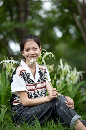 teen age sitting in the garden with white lily flower in handの写真素材