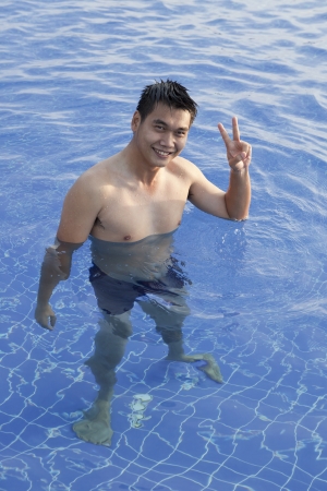man standing in water pool sign victory handの写真素材