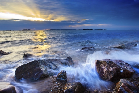 sunset on rock beach and splashing water の写真素材
