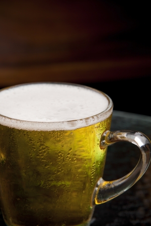close up bubble lager beer in mug  brown wood backgroundの写真素材