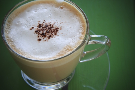 hot cappuccino coffee in cup on green tableの写真素材