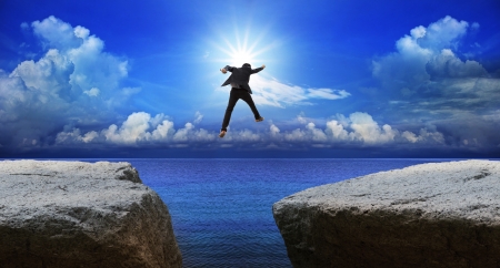business man jumping to next cliff with risk decisionの写真素材