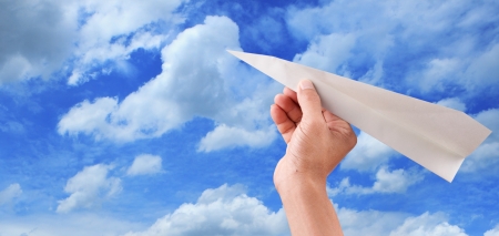 hand throwing paper plane to blue sky seem freedomの写真素材