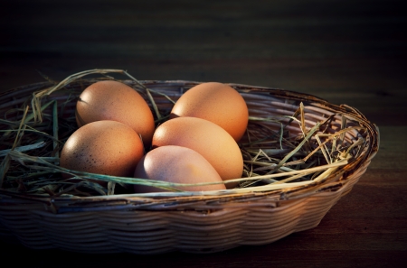 fresh eggs on rice straw with brown wood background の写真素材