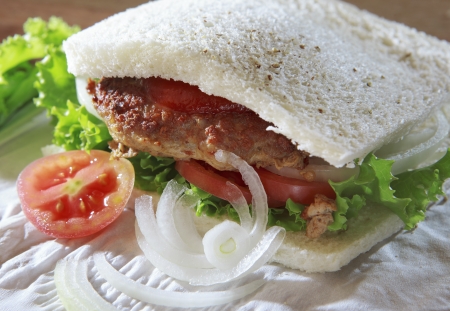  fried meat sandwich bread with green vegetable tomato and onion ring on top wood table ready to eating mealの写真素材