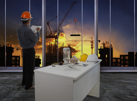 male engineer checking work flow in building construction site against beautiful dusky sky use for construction business and civil engineering の写真素材
