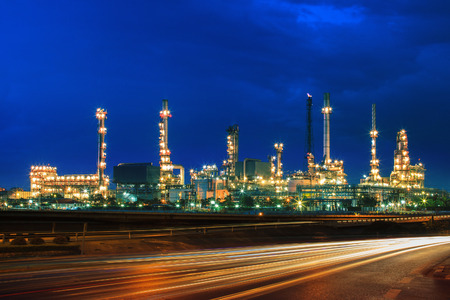 oil refinery plant against beautiful blue dusky sky and vehicle lighting on asphalt road use as land transport and oil power industry topic backgroundの写真素材
