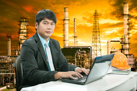 portrait young engineering  man sittin and working on laptop computer against oil refinery industry estateの写真素材