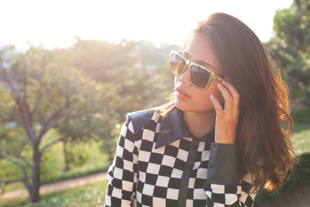 portrait of beautiful chick fashion woman wearing sun glasses against afternoon light with blur background and copy spaceの写真素材