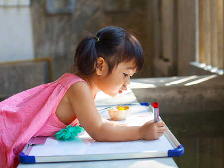 lovely kid practice for writing on white broad before class learning in pre kindergartenの写真素材