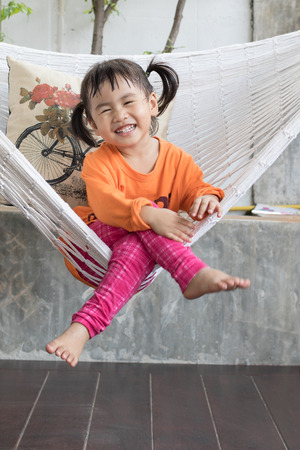 portrait of children toothy smiling and relaxing in clothes cradle at home living terraceの写真素材