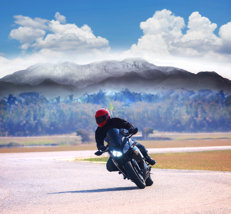 young man riding motorcycle on asphalt road against mountain highways background use for people activities on holiday vacation and motor sport hobbyの写真素材