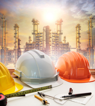 engineer working table plan, home model and writing tool equipment against building construction crane with evening dusky skyの写真素材