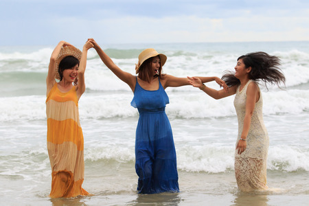 portrait of young asian woman with happiness emotion wearing beautiful dress dancing on sea beach and laughing joyful use for people relaxing vacation on destinationの写真素材