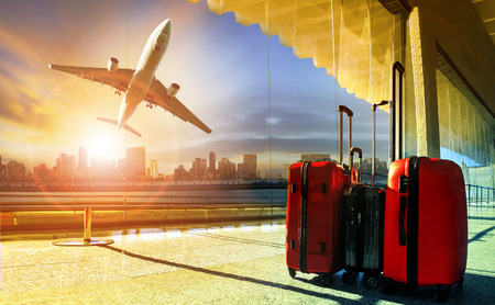 stack of traveling luggage in airport terminal and passenger plane flying over building in city