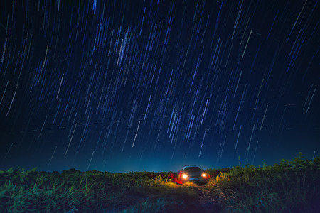 night scene of star tail and blue sky over car parking in agriculture fieldの写真素材